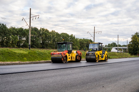 KYIV, UKRAINE - September 25, 2020: Two heavy asphalt road roller with heavy vibration roller compactor that press new hot asphalt on the roadway on a road construction site on a street.のeditorial素材