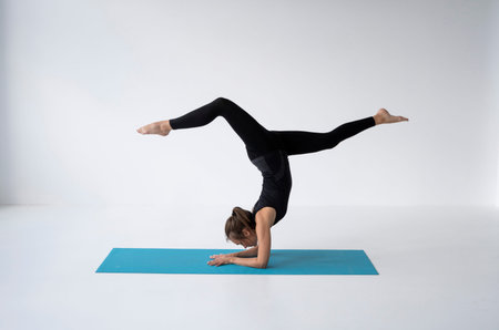 Young woman is practicing yoga in a studio. Slim young girl in a black sport wear is doing yoga...