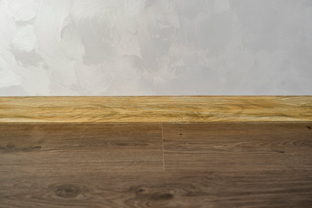 Laminate with plastic baseboard with a wooden texture. Newly installed wooden laminate flooring and baseboards in home. Modern design. Close up of plastic plinths on dark wooden oak floor parquet.の写真素材