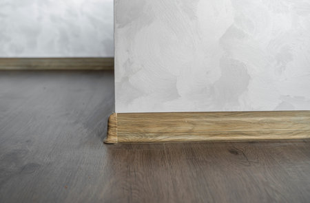 Laminate with plastic baseboard with a wooden texture. Newly installed wooden laminate flooring and...