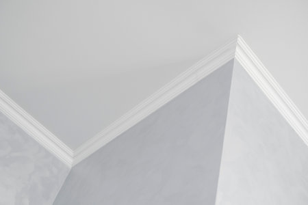 White ceiling with a white plinth in a room with gray painted walls. Decoration of the corner between the ceiling and the wall in the room. Ceiling molding in the interior. Detail of corner.の写真素材
