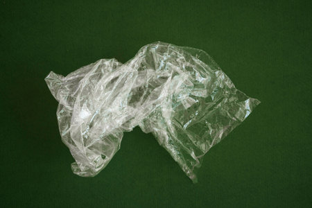 Crumpled plastic polyethylene bag on a green background. Contamination of the planet. Clear plastic...
