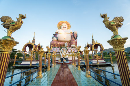 KOH SAMUI, THAILAND - January 10, 2020: Man with a camera stands on a bridge to a giant colorful buddha statue at wat plai laem temple on koh samui thailand.のeditorial素材