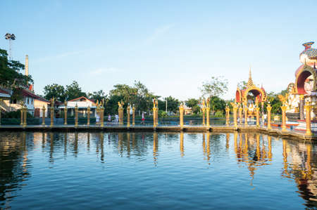 KOH SAMUI, THAILAND - January 10, 2020: Woman in a red dress standing on a bridge to a giant colorful buddha statue at wat plai laem temple on koh samui thailand.のeditorial素材