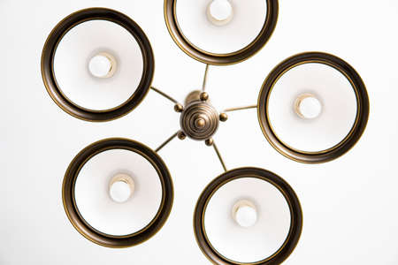 Bronze chandelier with five white glass lamp shades on a ceiling in a bedroom. Interior design.の写真素材