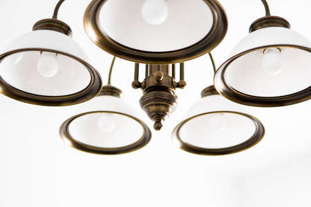 Bronze chandelier with five white glass lamp shades on a ceiling in a bedroom. Interior design.の写真素材