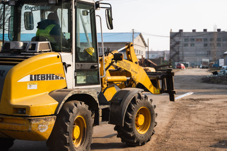 LUTSK, UKRAINE - May 10, 2020: Yellow wheel loader Excavator machine working at sawmill.
