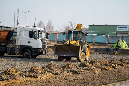LUTSK, UKRAINE - May 10, 2020: Yellow wheel loader Excavator machine and truck working at...