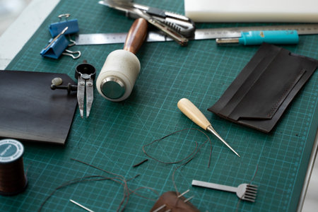 Mens hand working on the leather wallet in his workshop. Working process with a brown natural...