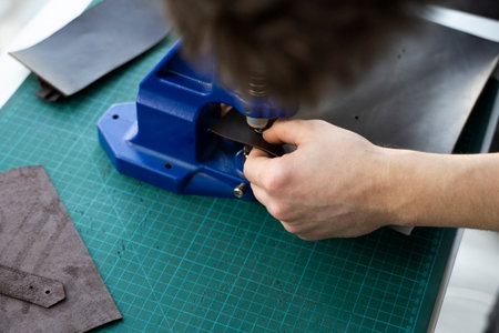 Artisan using hand press for setting snaps in leather for makes a wallet. Hand Pressure Snap Pressing Machine is using by craftsman in leather workshop.の写真素材