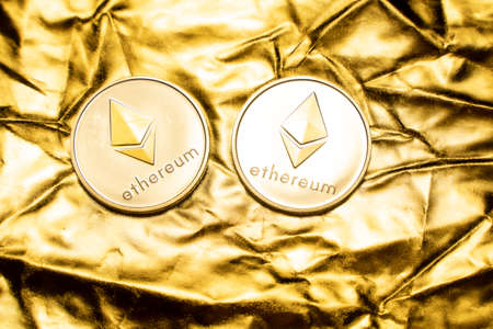 Gold ethereum coins on a golden background. Trading on the cryptocurrency exchange. Cryptocurrency Stock Market Concept. Virtual money concept. Mining or blockchain technology. Business concept.の写真素材