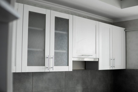 Modern minimalism style kitchen interior in monochrome tones. Custom kitchen with grey white facadesmdf and dark grey countertop with installed kitchen hood and sink. Modular kitchen from chipboard.の写真素材