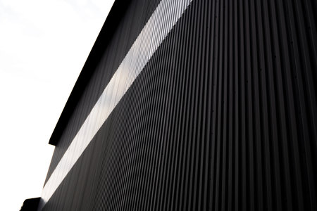 Black and white corrugated iron sheet used as a facade of a warehouse or factory. Texture of a...