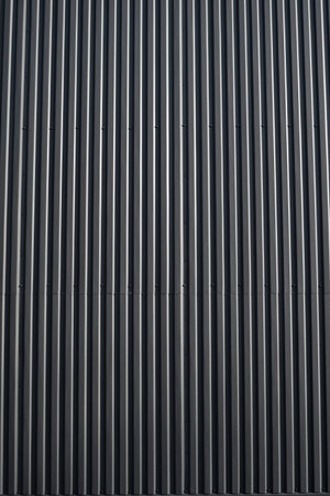 Black corrugated iron sheet used as a facade of a warehouse or factory. Texture of a seamless...