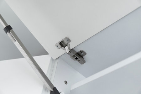 Metallic loop installed in a kitchen cabinet from a white chipboard.の写真素材