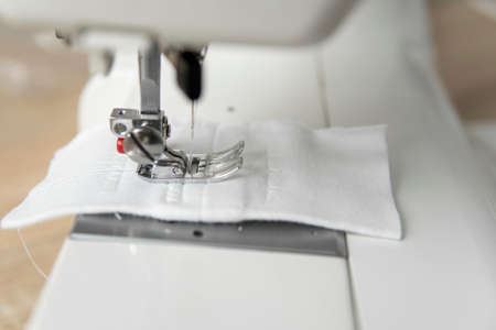 Sewing machine with with a white cloth on a wooden table.の写真素材