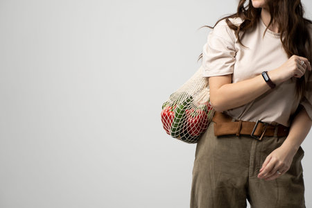 Girl is holding mesh shopping bag with vegetables, greens without plastic bags. Zero waste, plastic...