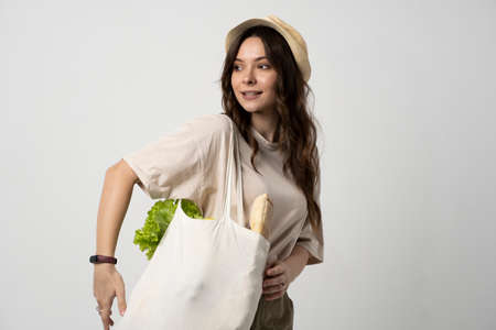 Woman holding textile grocery bag with vegetables. Zero waste concept. Package-free food shopping. Eco friendly natural bag with organic fruits and vegetables.の写真素材