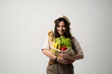 Portrait of young woman with a eco bag of vegetables, greens. Sustainable lifestyle. Eco friendly concept.の写真素材