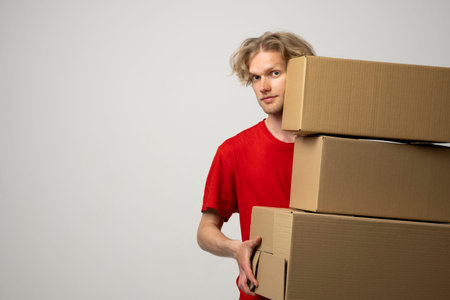 Courier in a red uniform holding a stack of cardboard boxes. Delivery man delivering postal packages...