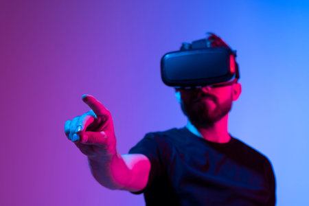 Amazed young bearded man, wearing high tech smart vr goggles, watching 360 degree video or playing a...