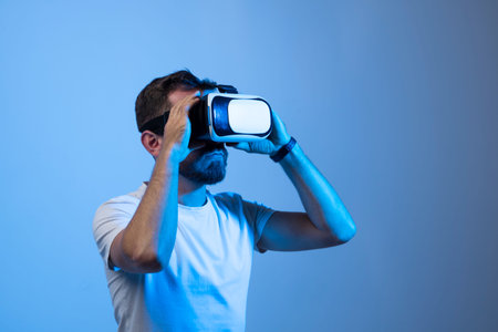 Attractive young man in black t-shirt wearing virtual reality headset or 3d glasses. Handsome male...