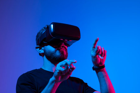 Happy and excited man playing racing video game with virtual reality headset in a metaverse world with a friends. Future technology concept.の写真素材