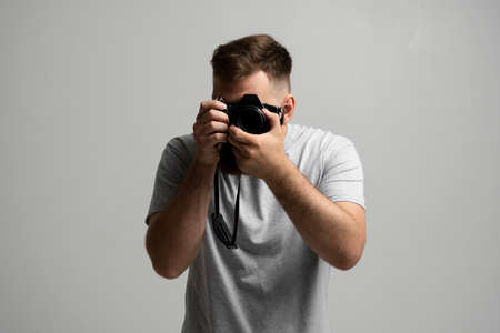Photography, creative, artist concept. Bearded professional photographer shooting on dslr mirrorless photo camera while working in studio.の写真素材