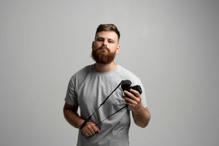 Portrait of handsome and confident bearded man photographer with a professional camera ready for...
