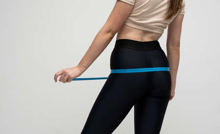The woman in sport outfit taking measurements of her body.の写真素材