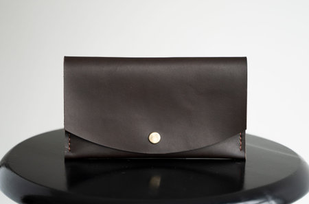 Mans handmade genuine leather wallet for banknotes and credit cards on a black surface with white...