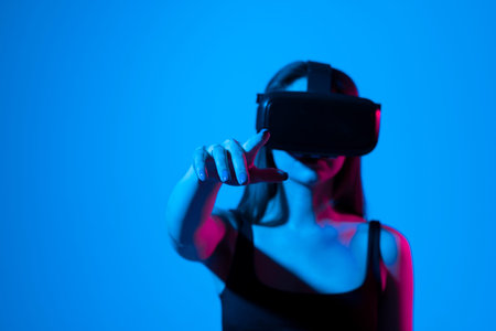 Excited young woman in VR headset exploring artificial computer world or playing video game at home...