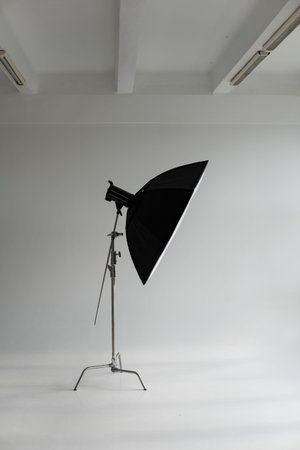 Professional photo flash light with a big softbox on a c-stand on a cyclorama in modern photo studio...