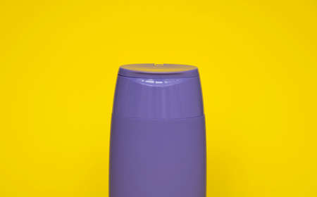 Violet plastic shampoo bottle isolated on yellow background. Skin care lotion. Bathing essential product. Shampoo bottle. Bath and body lotion. Fine liquid hand wash.の写真素材