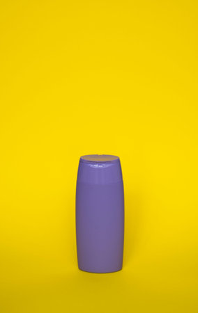Violet plastic shampoo bottle isolated on yellow background. Skin care lotion. Bathing essential...