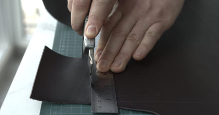 Working process of crafting a new handmade leather wallet in the leather workshop. Mans hands...