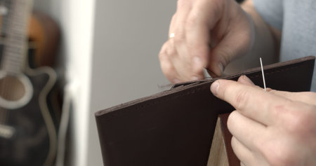 Man working with leather by needle. Genuine Leather. Sewing a purse. Leather work. Tools for sewing...