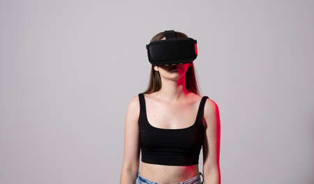 Happy young woman playing on VR glasses. Virtual reality concept with young girl having fun in virtual reality goggles. Metaverse.の写真素材