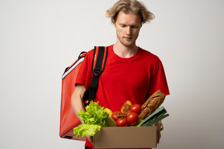 The guy delivers the basket full of groceries to the door of the house. Online shopping. Quality service of a restaurant.の写真素材