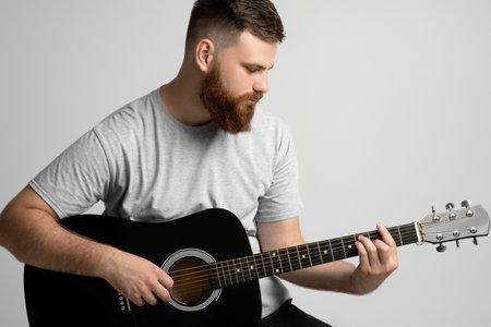 A young stylish men with a beard with a acoustic guitar on a white background. Music performer musician. Musical string instrument.の写真素材