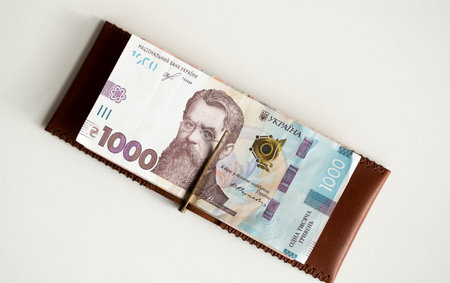 Ukrainian hryvnia money in leather money clip, wallet. Ukraine money on white background with. Currency of Ukraine. Accessories. Money, financess, economy, saving.の写真素材