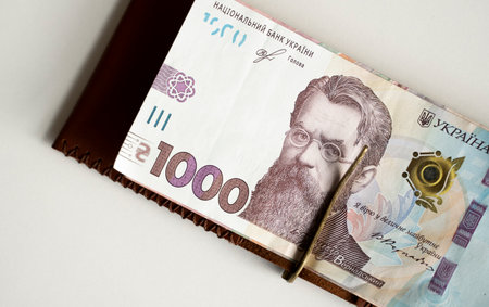 Brown leather money clip, purse with ukrainian hryvnia banknotes. Mens genuine leather wallet. Accessories. Money, financess, economy, saving.の写真素材