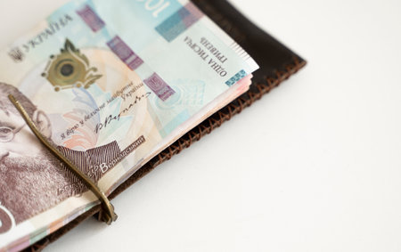 Ukrainian hryvnia money in leather money clip, wallet. Ukraine money on white background with. Currency of Ukraine. Accessories. Money, financess, economy, saving.の写真素材