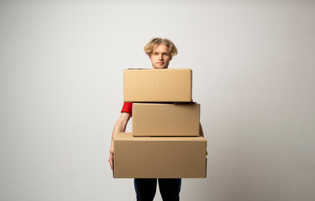 Young delivery man standing with lot of parcel post boxes isolated over white background.の写真素材