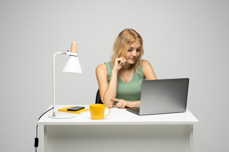 Smiling cheerful attractive young brunette woman 20s working on laptop pc computer. Happy brunette business lady using laptop. Successful entrepreneurship and career concept.の写真素材