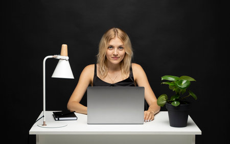 Cheerful business lady working on laptop in office. Happy blonde businesswoman work in workplace. Attractive female employee office worker smile.の写真素材