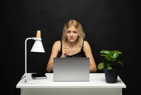 Frustrated sad woman feeling tired worried about problem sitting in office with laptop. Stressed depressed girl troubled with reading bad news online.の写真素材