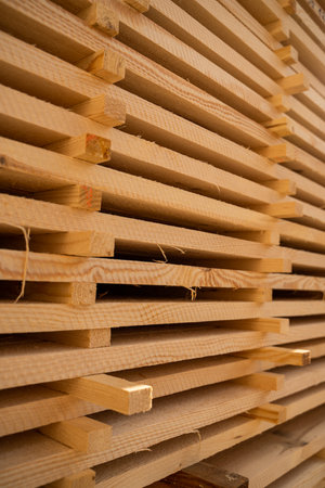 Stacked wooden planks in close-up at a outdoor lumber warehouse. Piles of wooden boards in the sawmill, planking. Warehouse for sawing boards on a sawmill outdoors. Wood industry.の写真素材