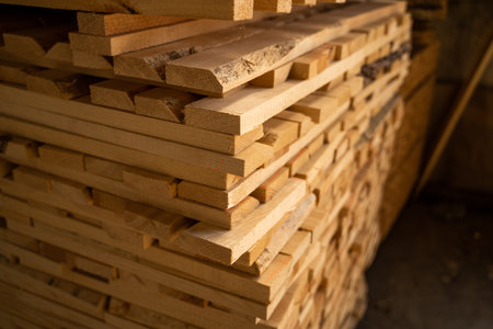Stacked wooden planks in close-up at a outdoor lumber warehouse. Background of boards. Wood industry.の写真素材