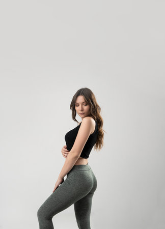 Brunette woman in a dark sporty outfit on white background.の写真素材